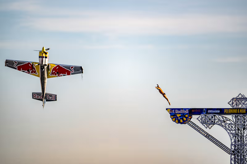 Aeronave acrobática en vuelo de precisión junto a un parapentista